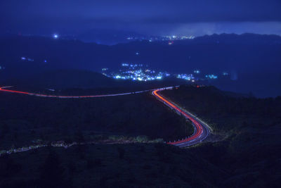 Light trails on road amidst land at night