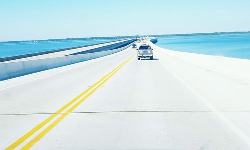 Car on road by sea against clear sky