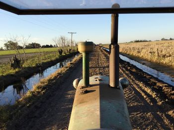 Footpath on grassy field against clear sky