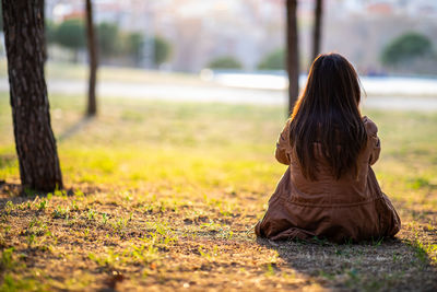 Rear view of woman sitting on land