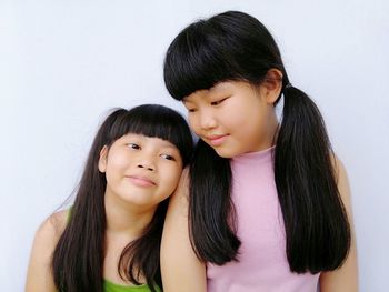 Smiling sisters against white background