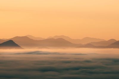 Scenic view of silhouette mountains against orange sky