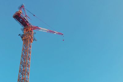 Low angle view of crane against clear blue sky