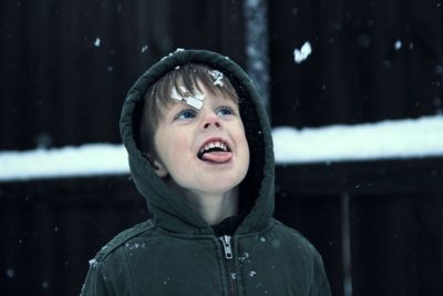 Close-up portrait of smiling boy in snow