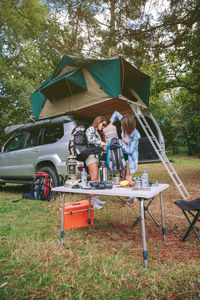 Friends standing by car in forest