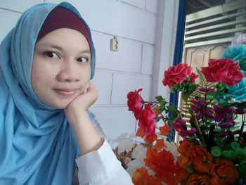 Woman with hand in chin sitting by artificial flowers