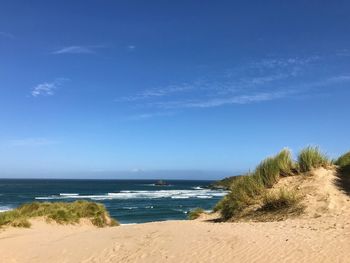 Scenic view of beach against blue sky