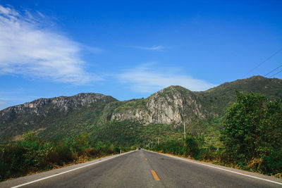 Road by mountains against sky