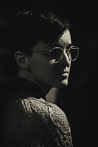 Portrait of young woman wearing sunglasses against black background