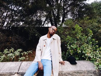 Young man sitting against tree