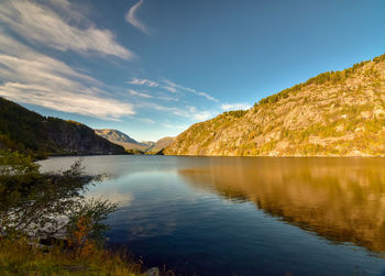 Scenic view of lake by mountains against sky