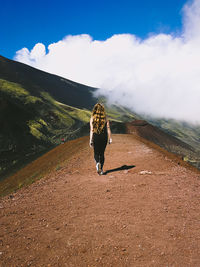 Rear view of woman walking on mountain against sky