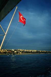 Red flag over sea against sky in city