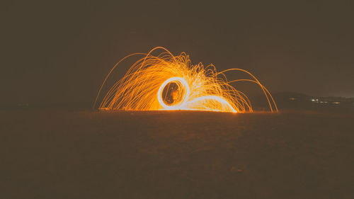 Illuminated ferris wheel on land against sky at night