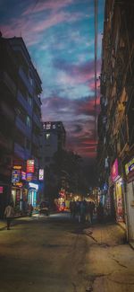 Illuminated city street against sky at night