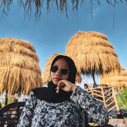 Portrait of young woman wearing sunglasses standing against sky