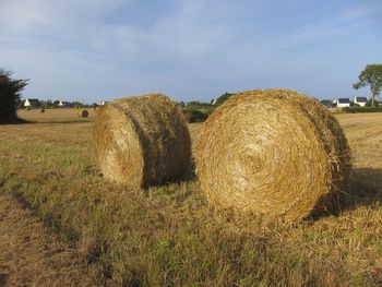 Hay bales on field against sky