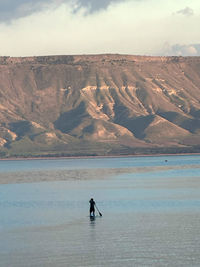 Rear view of man on boat on lake against sky