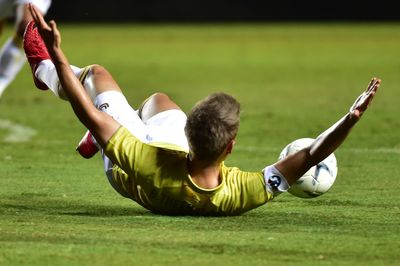 Rear view of man playing soccer on grass