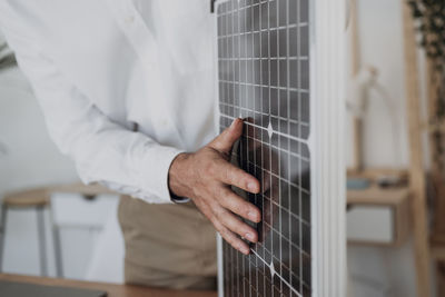 Hand of engineer touching solar panel in office