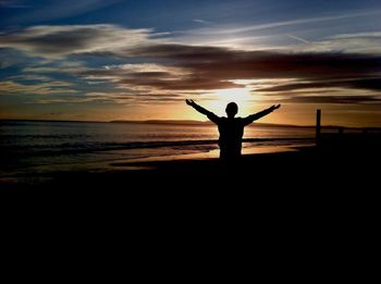 Silhouette man standing on beach against sky during sunset