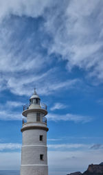 Low angle view of lighthouse by building against sky