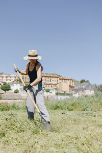 Farm worker with rake cleaning field on sunny day