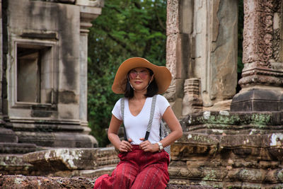 Full length of a smiling young woman sitting in temple