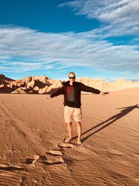 Portrait of man standing on desert against cloudy sky