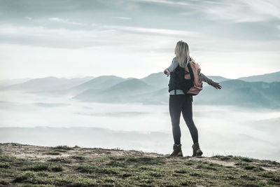 Happy woman tourist stay on green grass on peak of mountain and look on nice view. concept freedom.