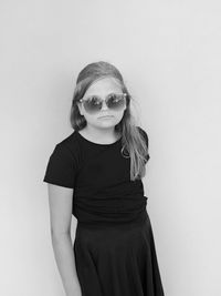 Portrait of young woman wearing sunglasses against white background