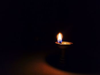 Close-up of lit candle in darkroom