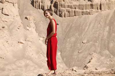 Portrait of woman standing by red umbrella on land