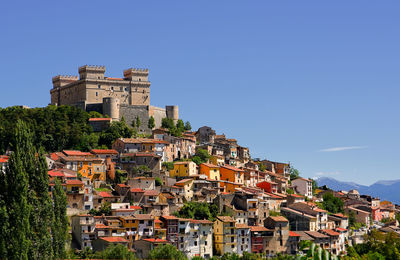 Buildings in city against clear blue sky