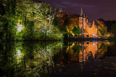 Reflection of trees and church on river at night