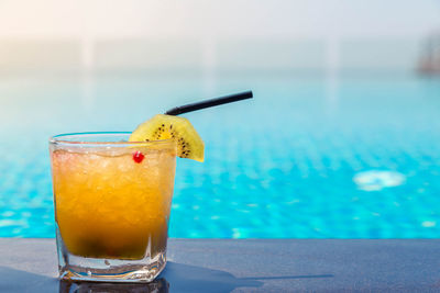 Close-up of drink on table against swimming pool