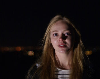 Portrait of young woman with teary eyes at night