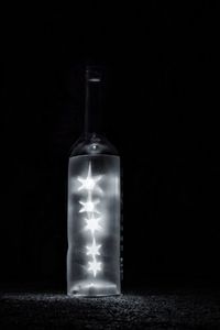 Close-up of illuminated bottle against black background