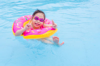 Portrait of girl gesturing peace sign while swimming in pool