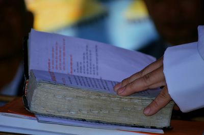 Cropped hand touching holy book in darkroom