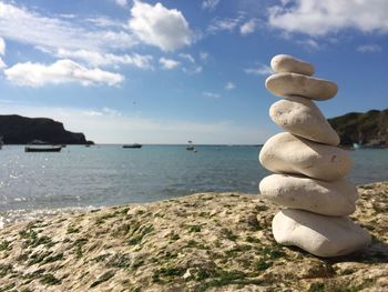 Stack on pebbles on rock by sea against sky