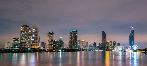 Illuminated buildings in city against sky