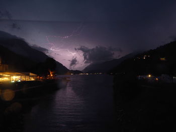 Scenic view of illuminated sea against sky at night