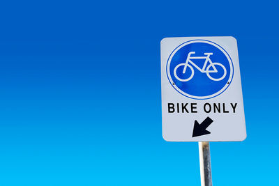 Low angle view of road sign against blue sky