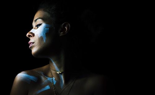 Woman with face paint against black background