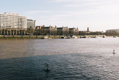 Scenic view of river by buildings against sky