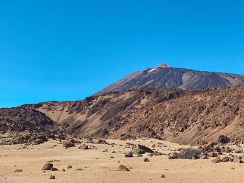 Scenic view of arid landscape against clear blue sky