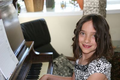 Portrait of smiling girl by piano