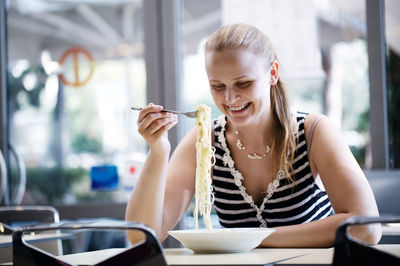 Smiling woman enjoying spaghetti at restaurant