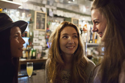 Portrait of a smiling young woman drinking from glass at restaurant